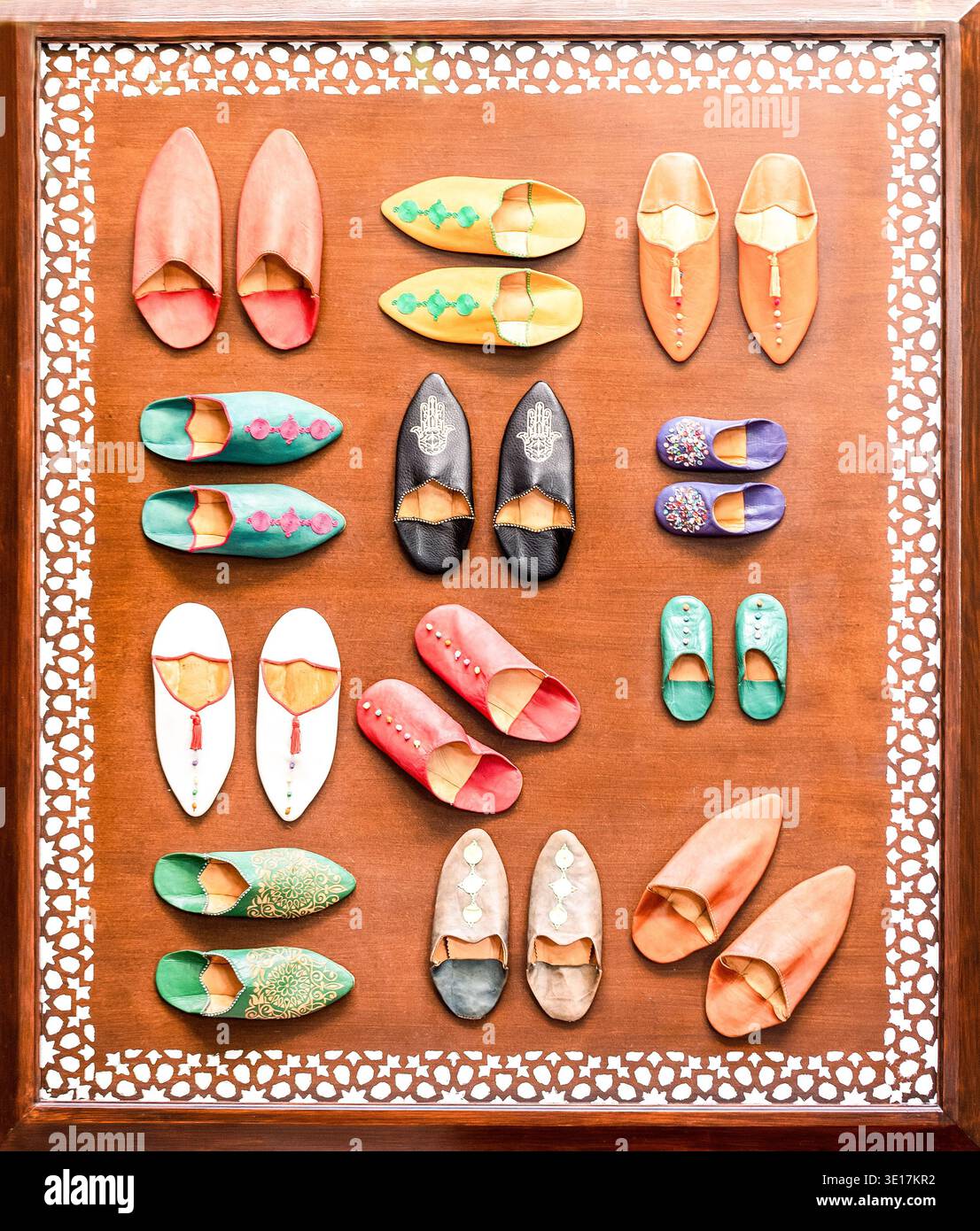 Une collection vibrante de chaussures marocaines traditionnelles faites à la main dans différentes couleurs et designs présentés sur un fond à motifs à Marrakech, Mo Banque D'Images