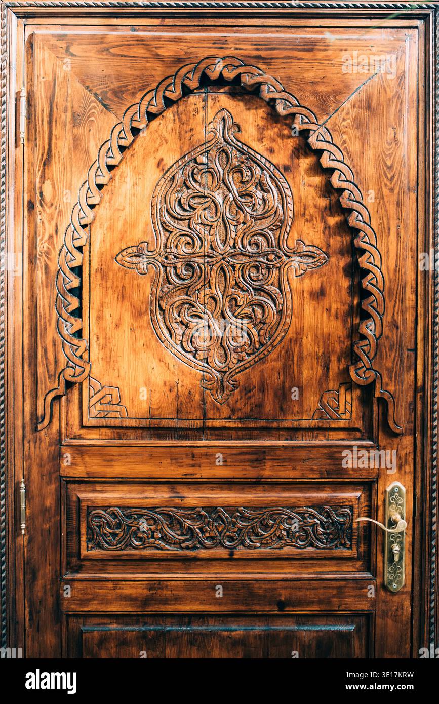 Les détails complexes d'une porte en bois magnifiquement sculptée à Marrakech, Maroc. Ce design exquis met en valeur l'artisanat marocain et culturel A. Banque D'Images