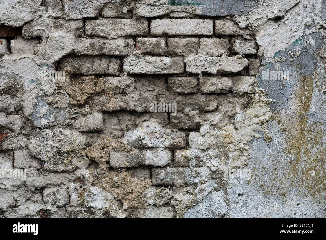 Vieux mur de briques endommagé avec plâtre gris pelable. Fond urbain altéré montrant mortier en ruine et texture grunge industrielle Banque D'Images