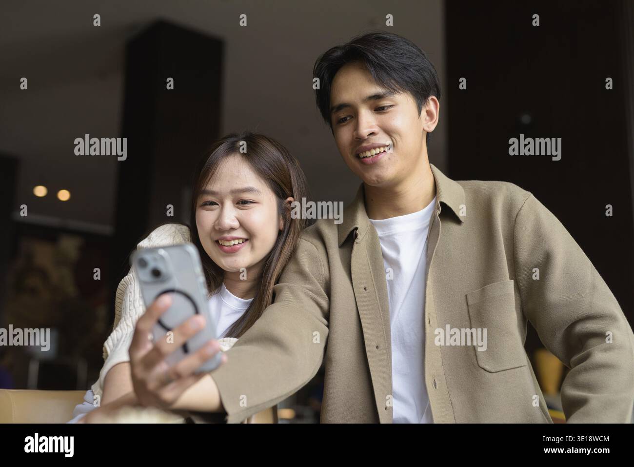 Portrait d'un jeune couple asiatique heureux prenant selfie dans un café avec smartphone Banque D'Images