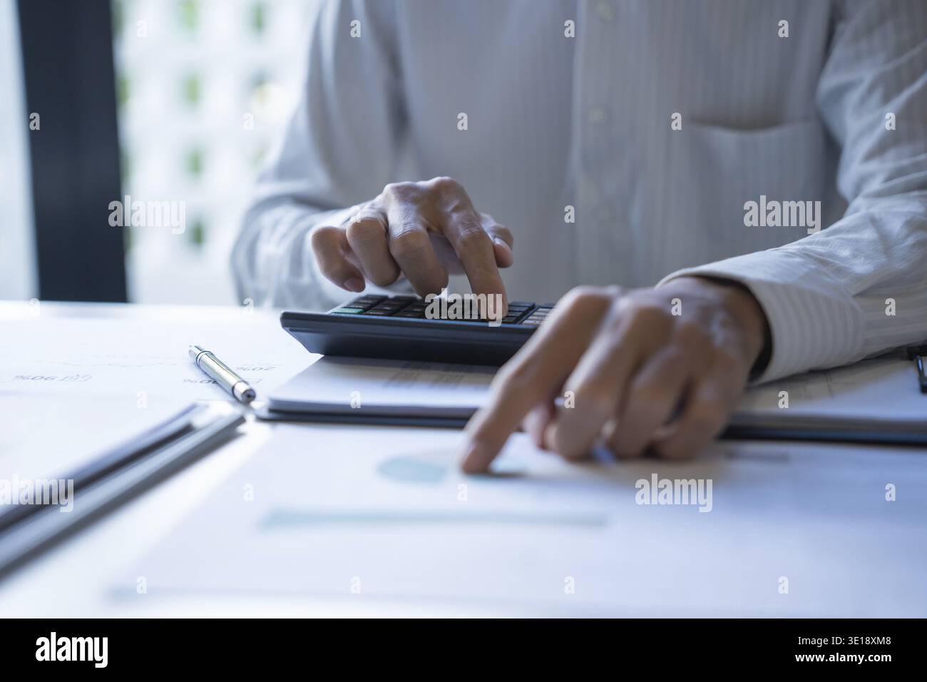 Professionnel masculin utilisant la calculatrice pour l'analyse du budget d'entreprise Banque D'Images