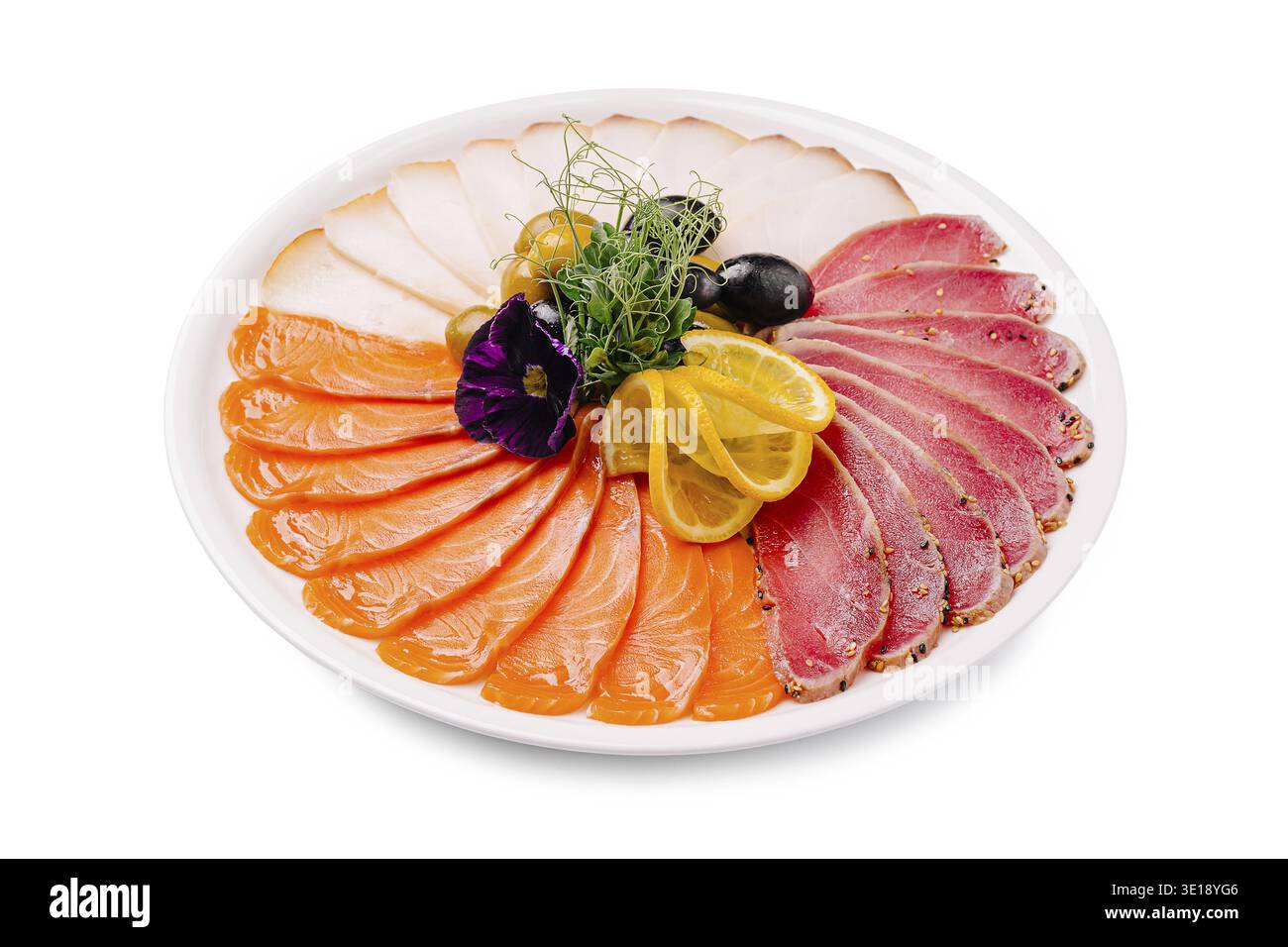 Un plat magnifiquement arrangé avec du saumon finement coupé en tranches, du thon en croûte de poivre et des tranches de viande blanche, garni de tranches de citron, noir et gree Banque D'Images