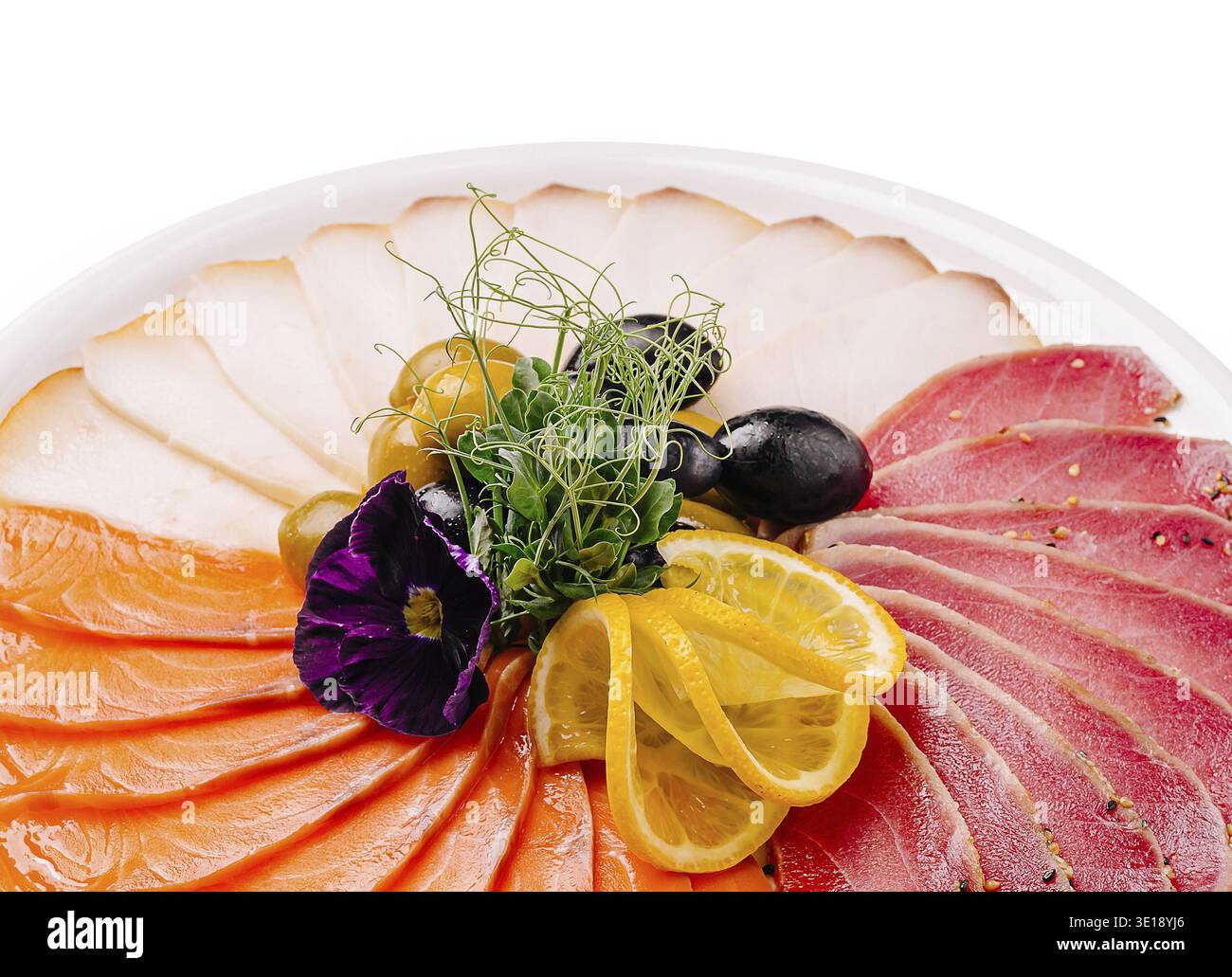 Un plat magnifiquement arrangé avec du saumon finement coupé en tranches, du thon en croûte de poivre et des tranches de viande blanche, garni de tranches de citron, noir et gree Banque D'Images