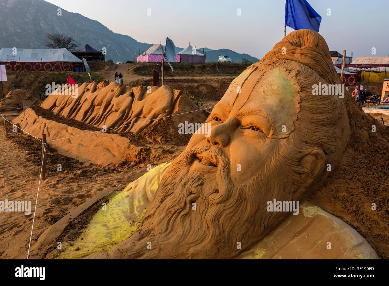 La foire aux chameaux de Pushkar, dispose d'une grande tête d'art de sable d'un homme barbu avec une rangée de chameaux sculptés et des tentes situées au loin. Pushkar Rajasth Banque D'Images