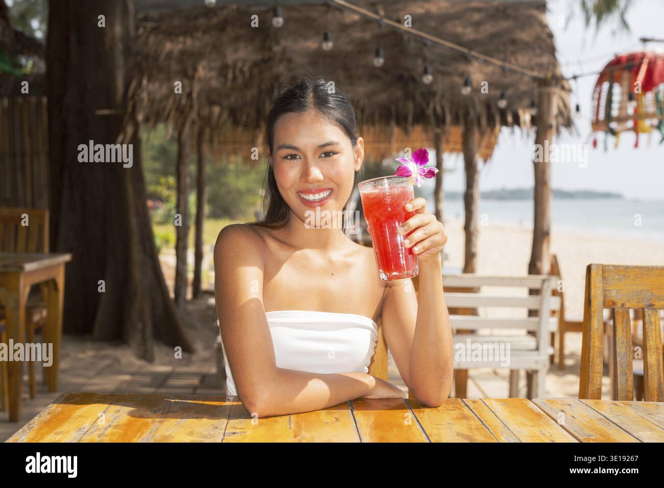 Jeune femme buvant une boisson de pastèque à la plage en Thaïlande Banque D'Images