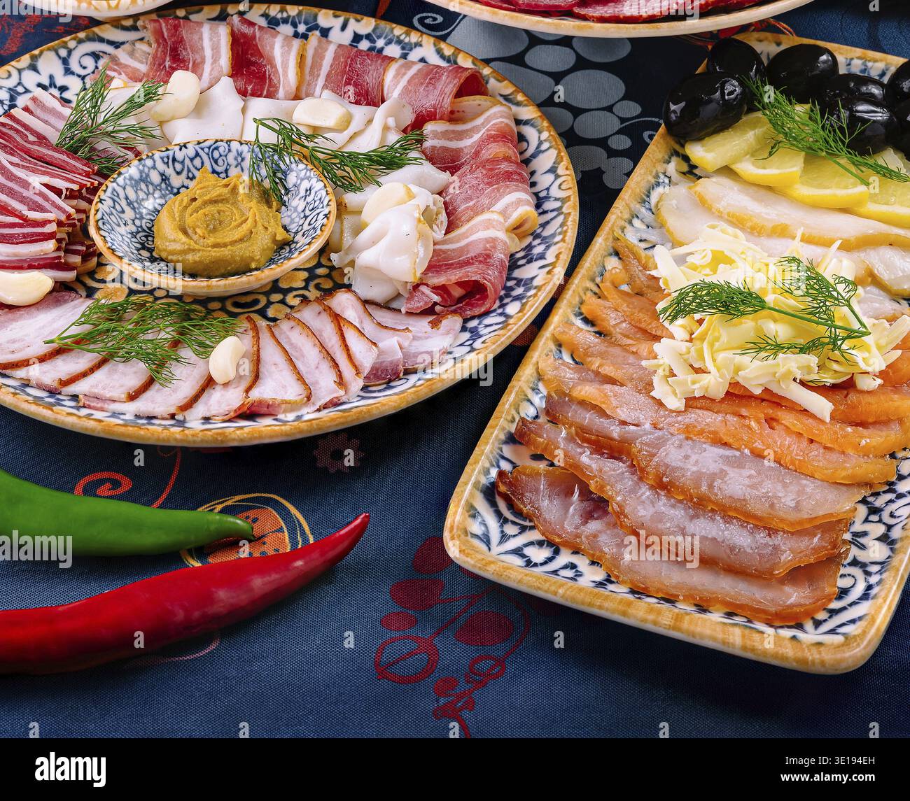 Des assiettes avec une variété d'entrées de viande fumée et de poisson sont disposées sur une table avec une nappe bleue Banque D'Images