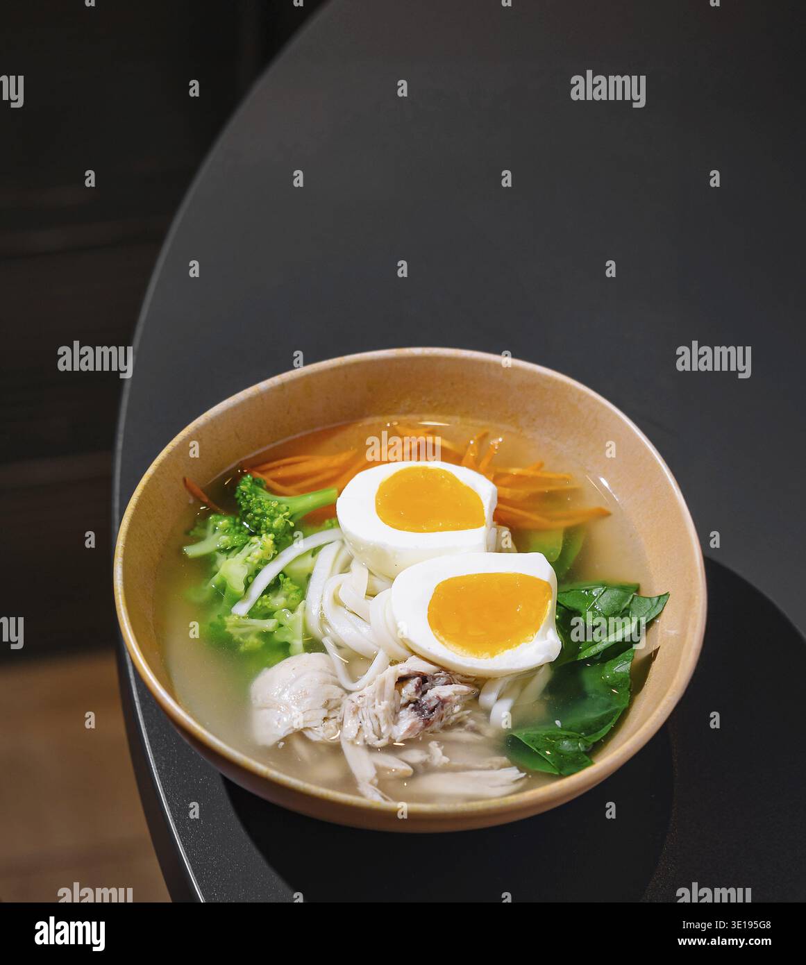 Soupe salée de nouilles au poulet avec légumes et œufs servie dans un cadre moderne de restaurant Banque D'Images
