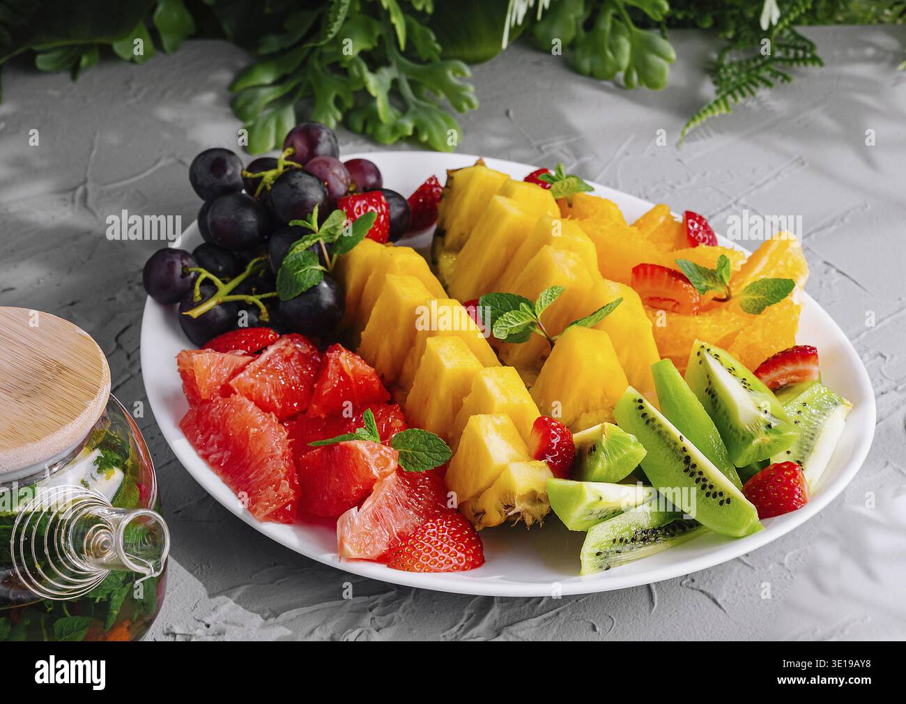 Plateau de fruits et pot en verre de thé vert sur pierre Banque D'Images