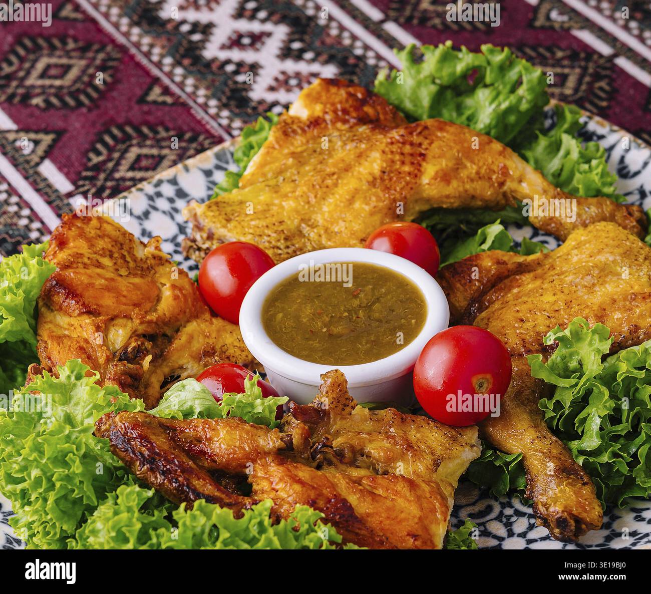 Délicieux poulet rôti sur un lit de laitue avec tomates et sauce trempette Banque D'Images