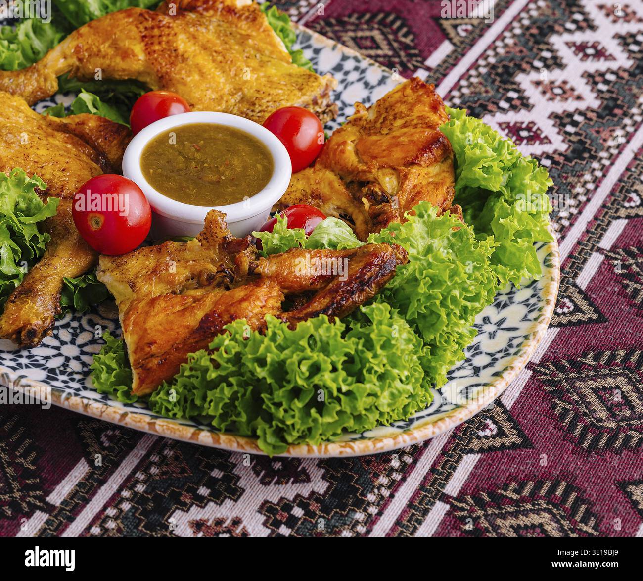 Délicieux poulet rôti sur un lit de laitue avec tomates et sauce trempette Banque D'Images