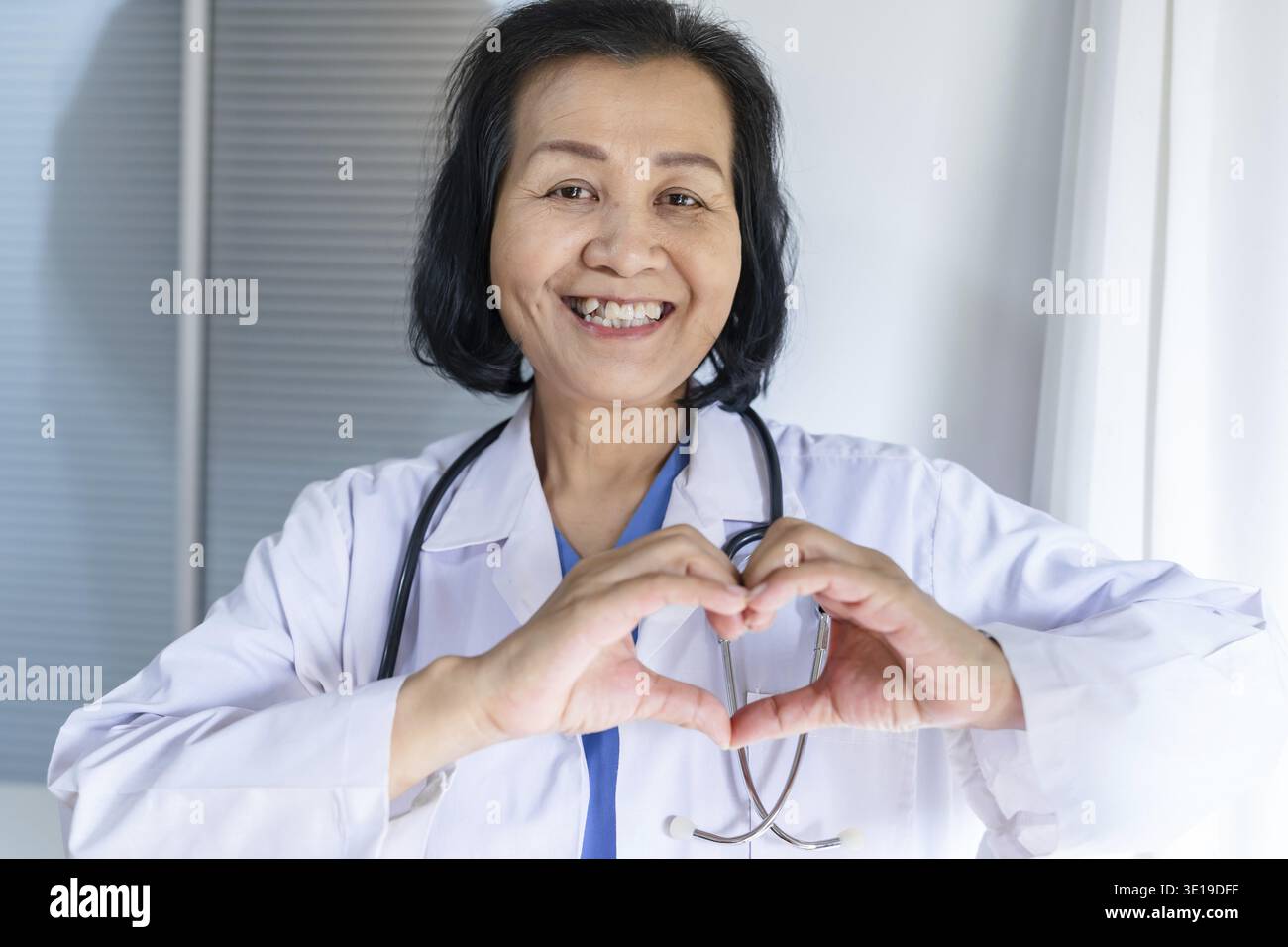 Cardiologue soutient le cœur femme asiatique senior médecin portant des lunettes et uniforme. portrait de vieilles femmes asiatiques matures professionnelles médicales Banque D'Images