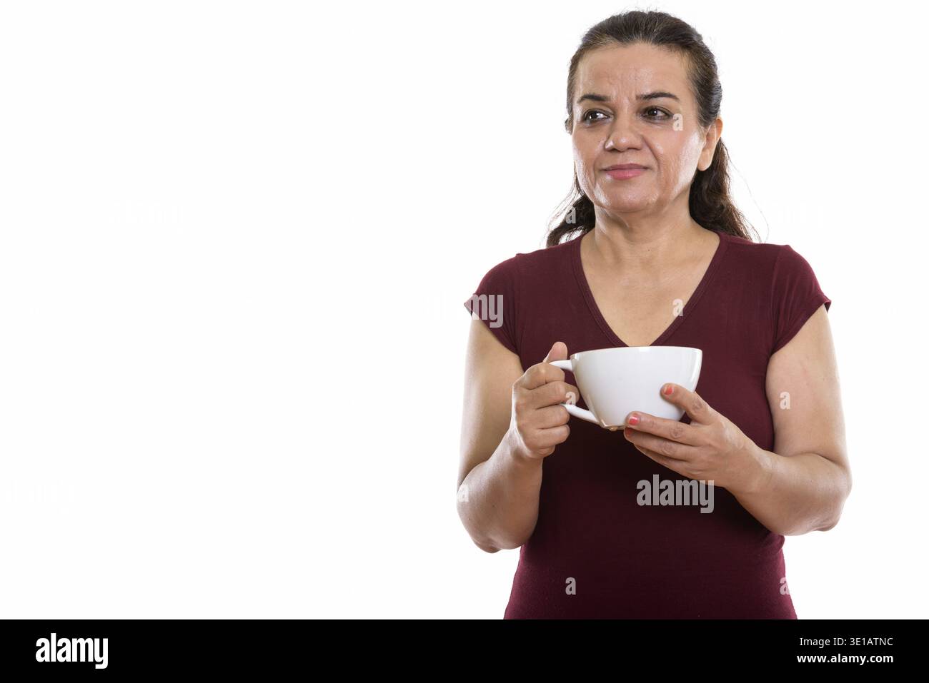 Photo studio d'une femme persane mûre pensant tout en tenant le café cuvette Banque D'Images