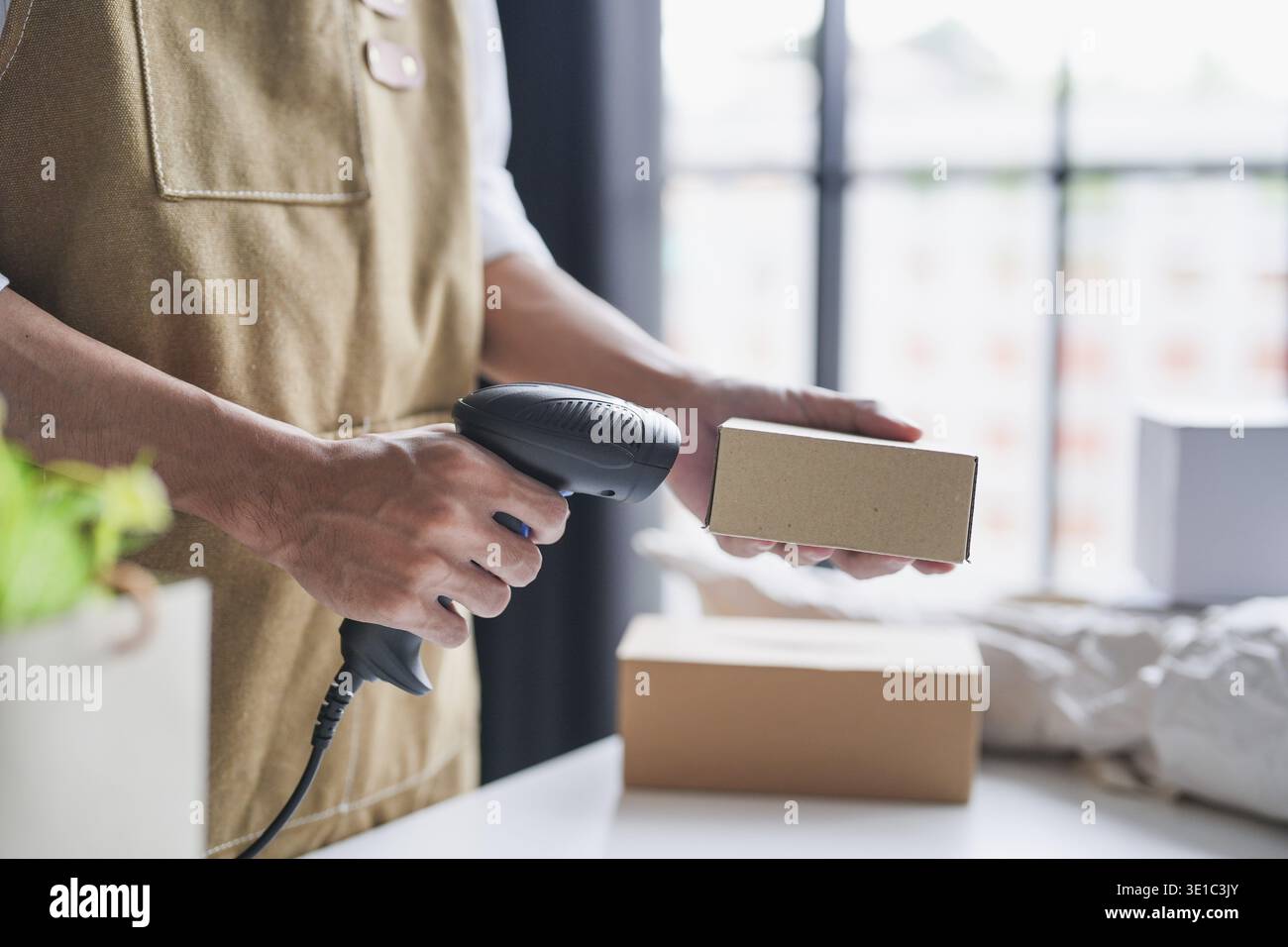 Propriétaire de petite entreprise asiatique utilisant un lecteur de codes-barres portable pour vérifier et gérer les stocks de produits dans un magasin de détail local pendant les opérations de l'après-midi Banque D'Images
