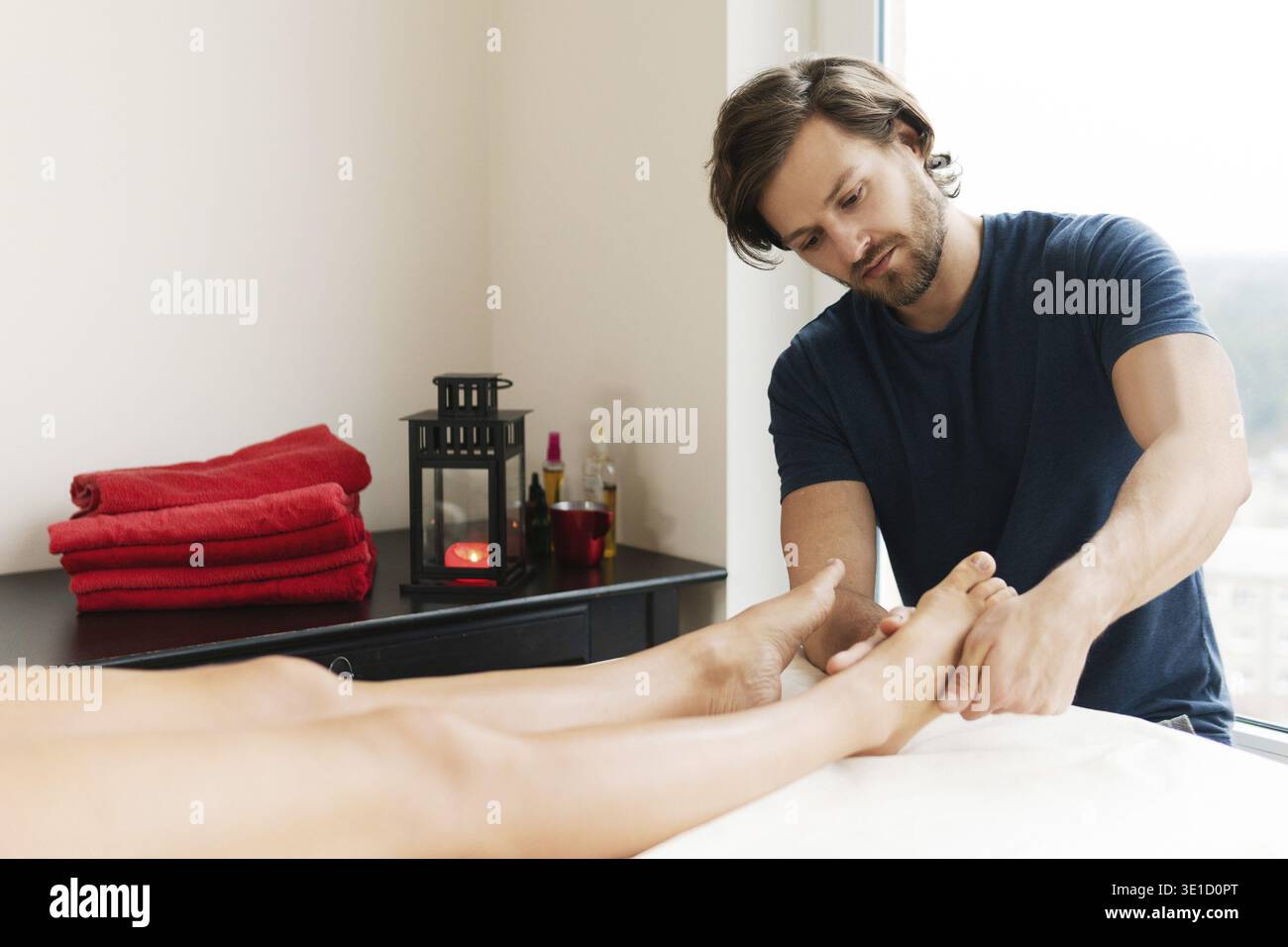 Professionnel beau masseur barbu homme pendant le massage des pieds féminins Banque D'Images