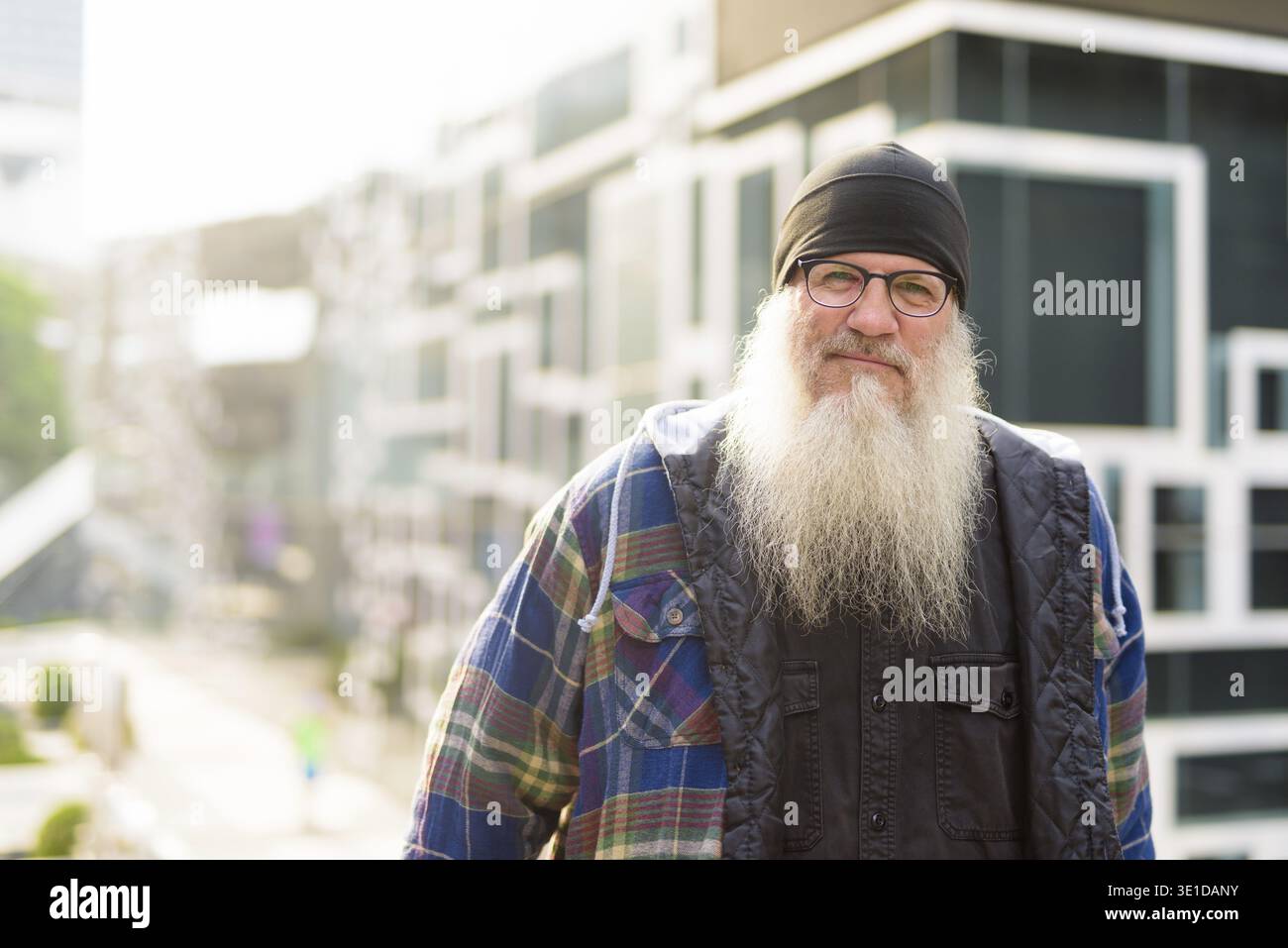 Portrait d'homme hipster mûr beau barbu contre le mur avec un design abstrait dans les rues de la ville à l'extérieur Banque D'Images