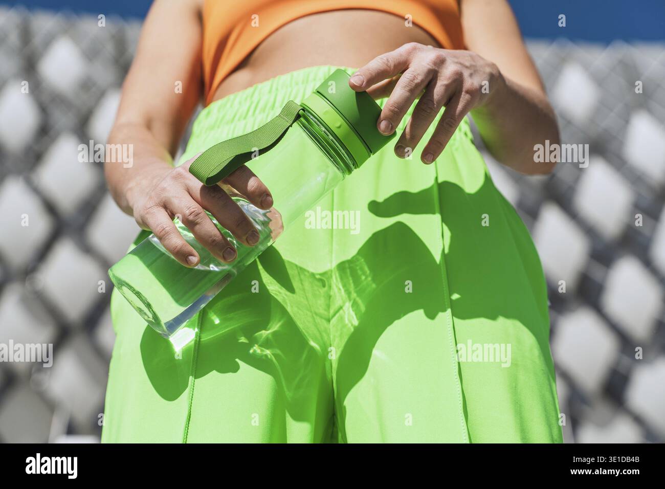 Gros plan des mains féminines avec une bouteille d'eau réutilisable verte Banque D'Images
