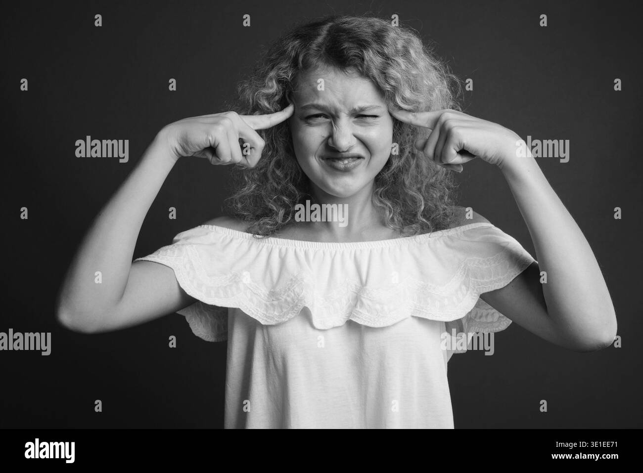 Studio shot of young Beautiful woman with blonde cheveux bouclés contre l'arrière-plan gris Banque D'Images