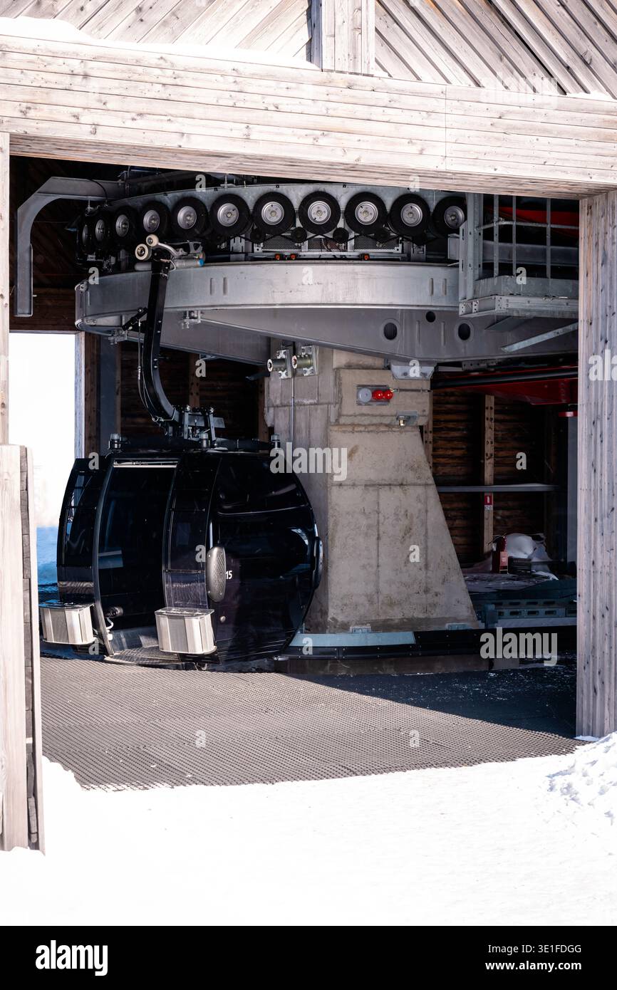 Une cabine de gondole se trouve à une station de montagne enneigée entourée de machinerie et de structure de levage visibles Banque D'Images