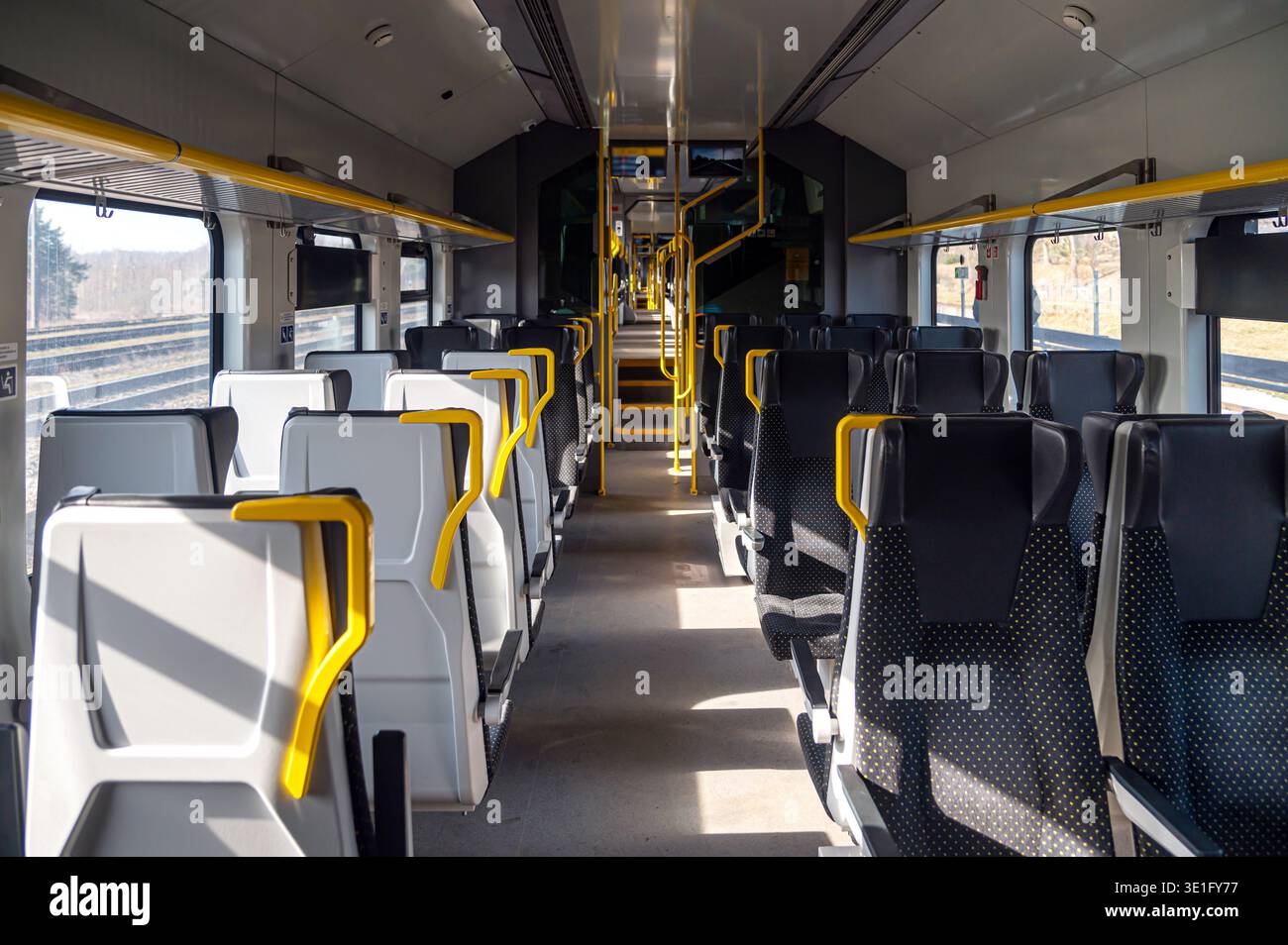 Les sièges sont vacants dans la cabine du train avec des lumières vives et une vue dégagée sur l'extérieur. Banque D'Images