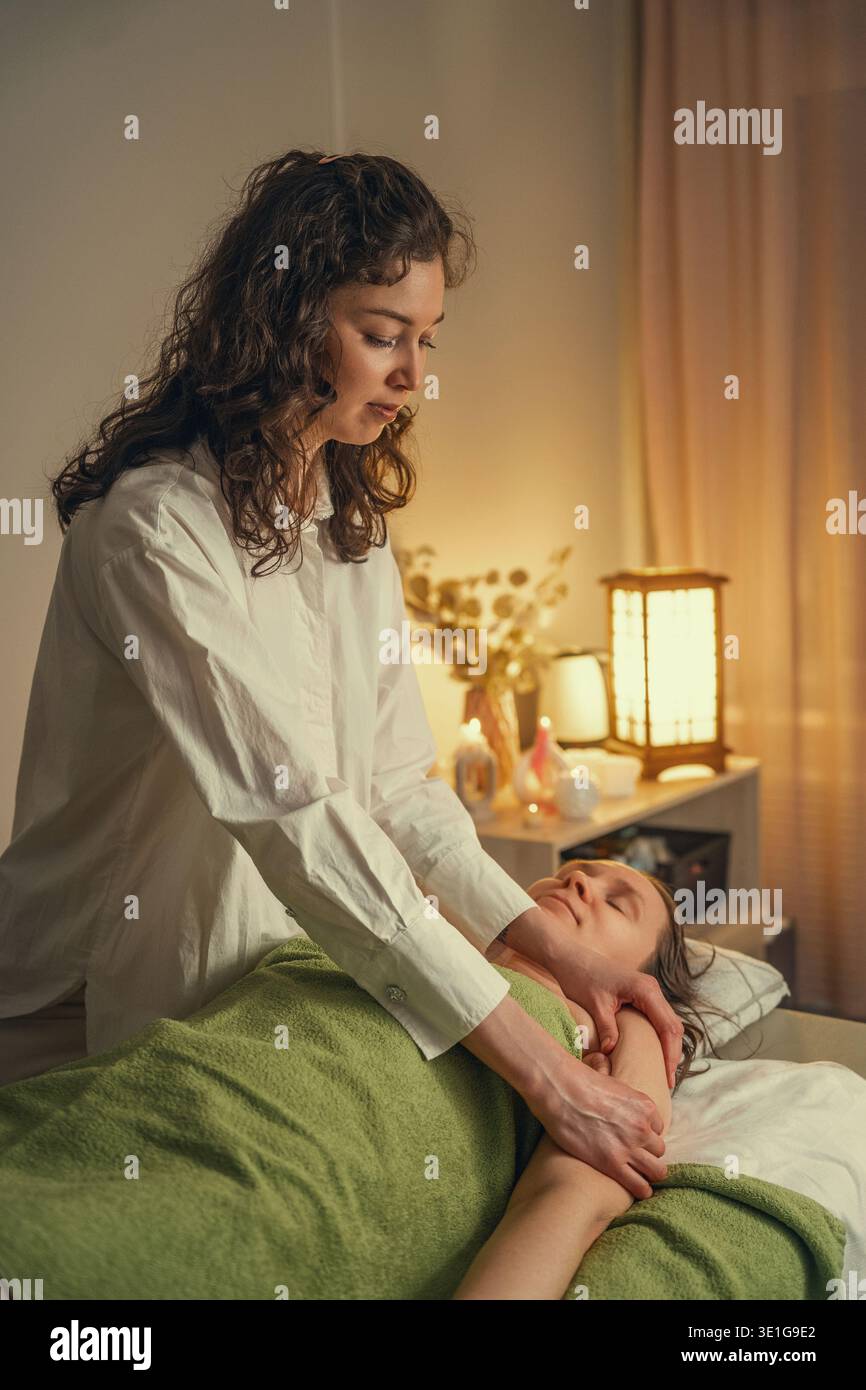 Thérapeute professionnel effectuant un massage des épaules dans un spa relaxant. Banque D'Images