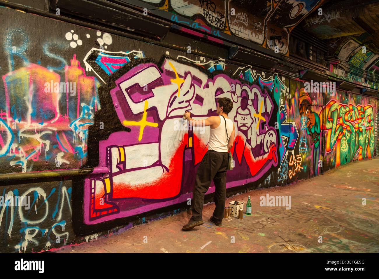 Un artiste graffiti au travail dans Leake Street Graffiti tunnel, célèbre espace d'art urbain situé sous la gare de Waterloo à Londres Banque D'Images