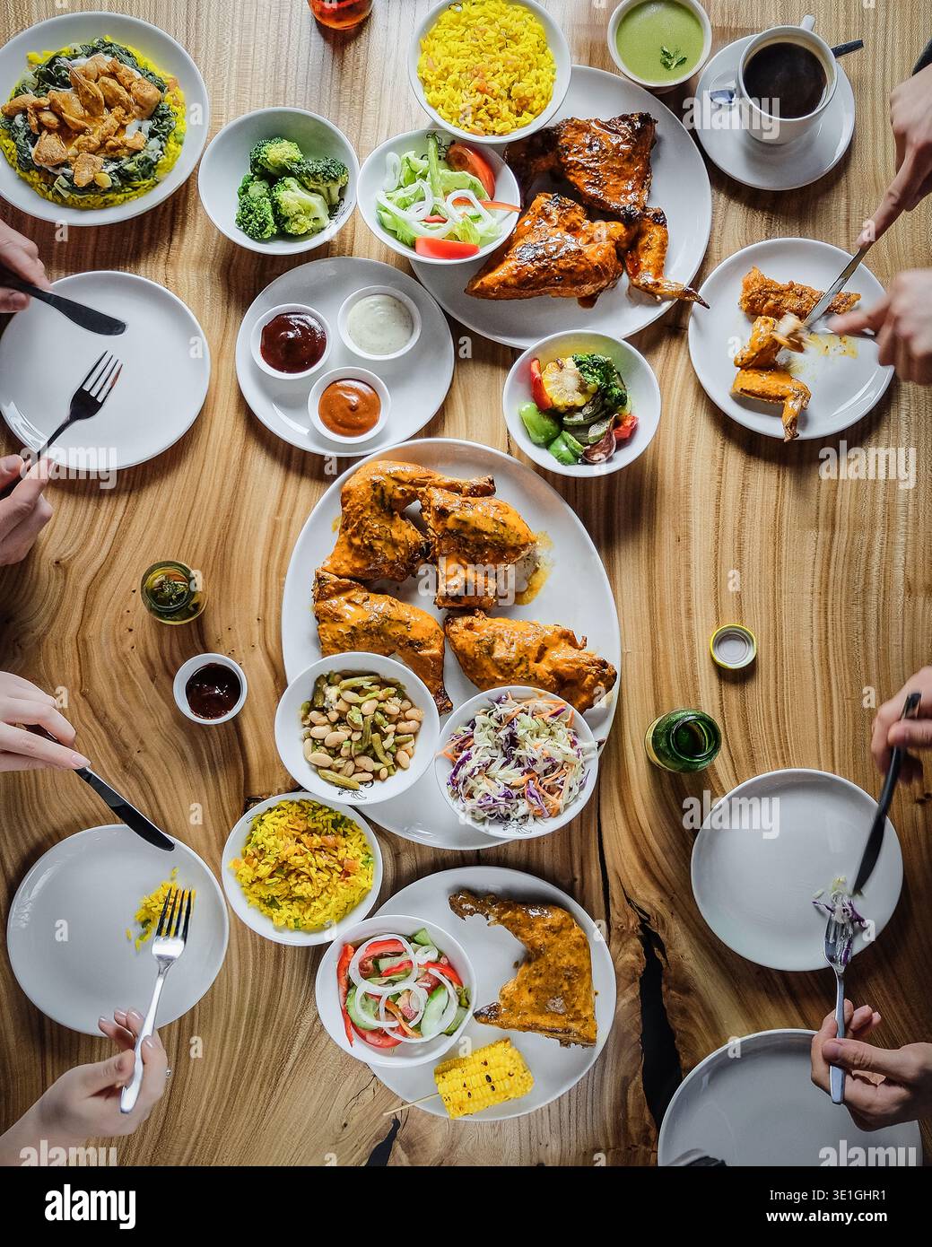 Fête partagée sur la table en bois rustique. Repas communautaire animé avec poulet frit et salades fraîches Banque D'Images