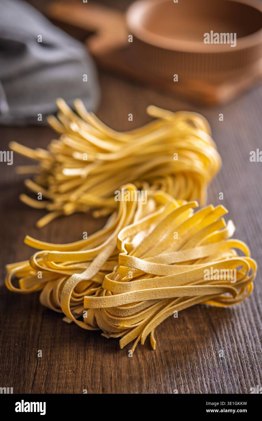 Les brins de pâtes fettuccine reposent sur une surface blanche, paraissant doux et frais. Ce type de pâtes est souvent utilisé dans divers plats. Banque D'Images