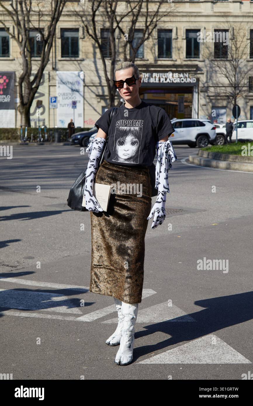 MILAN, ITALIE - 2 MARS 2025 : Jeanna Krichel avec t-shirt Supreme noir avec motif visage, jupe en velours bronze et gants noirs et blancs avant Giorgi Banque D'Images