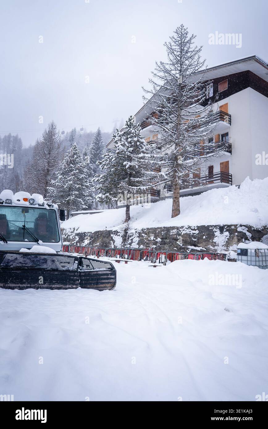 Chute de neige au Lodge alpin de San Domenico avec chat à neige en opération Banque D'Images
