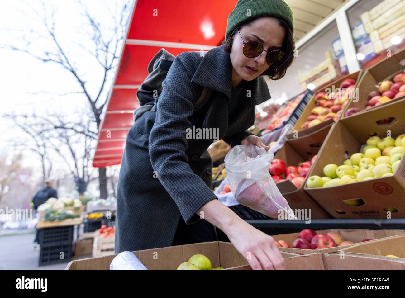 Femme atteignant des pommes au stand de fruits extérieur Banque D'Images