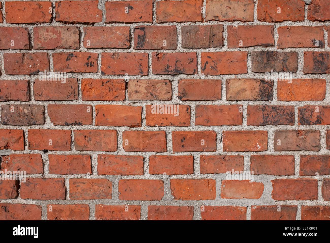 Texture murale en briques rouges avec différentes nuances et joints de mortier, présentant un aspect rustique et industriel adapté aux fonds Banque D'Images