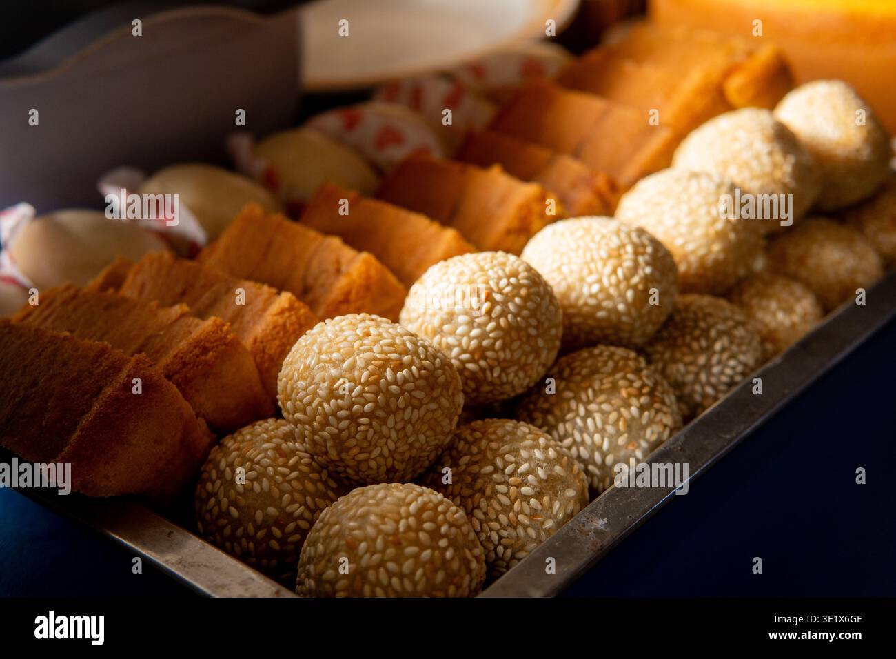 Gros plan de divers en-cas colorés, y compris gâteau de marbre tranché, onde-onde, et petits pains cuits à la vapeur soigneusement organisés pour une célébration. Banque D'Images