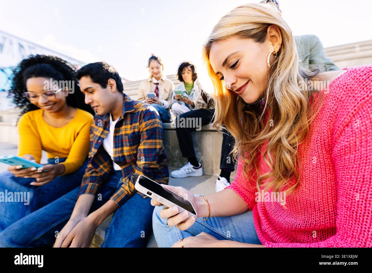 Divers jeunes amis étudiants utilisant des téléphones intelligents ensemble à l'extérieur Banque D'Images