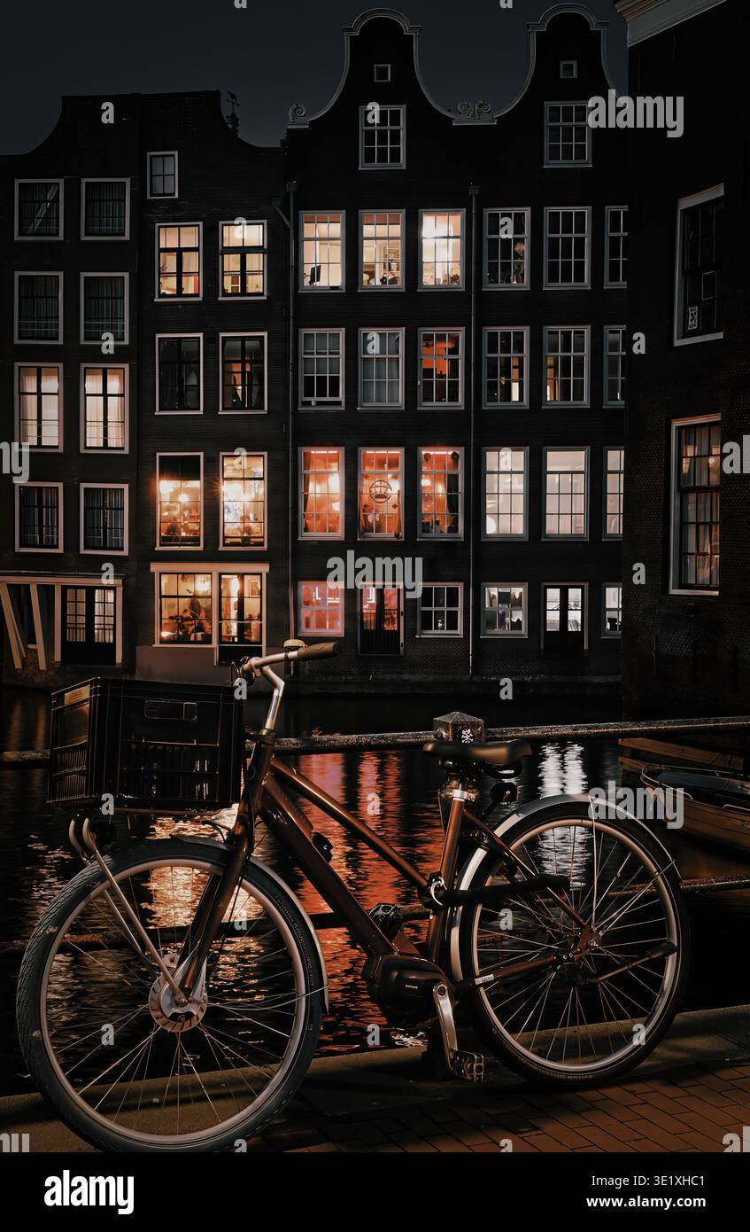 Un vélo enchaîné à l'un des ponts du quartier rouge d'Amsterdam, avec des maisons à pignon traditionnelles en arrière-plan Banque D'Images