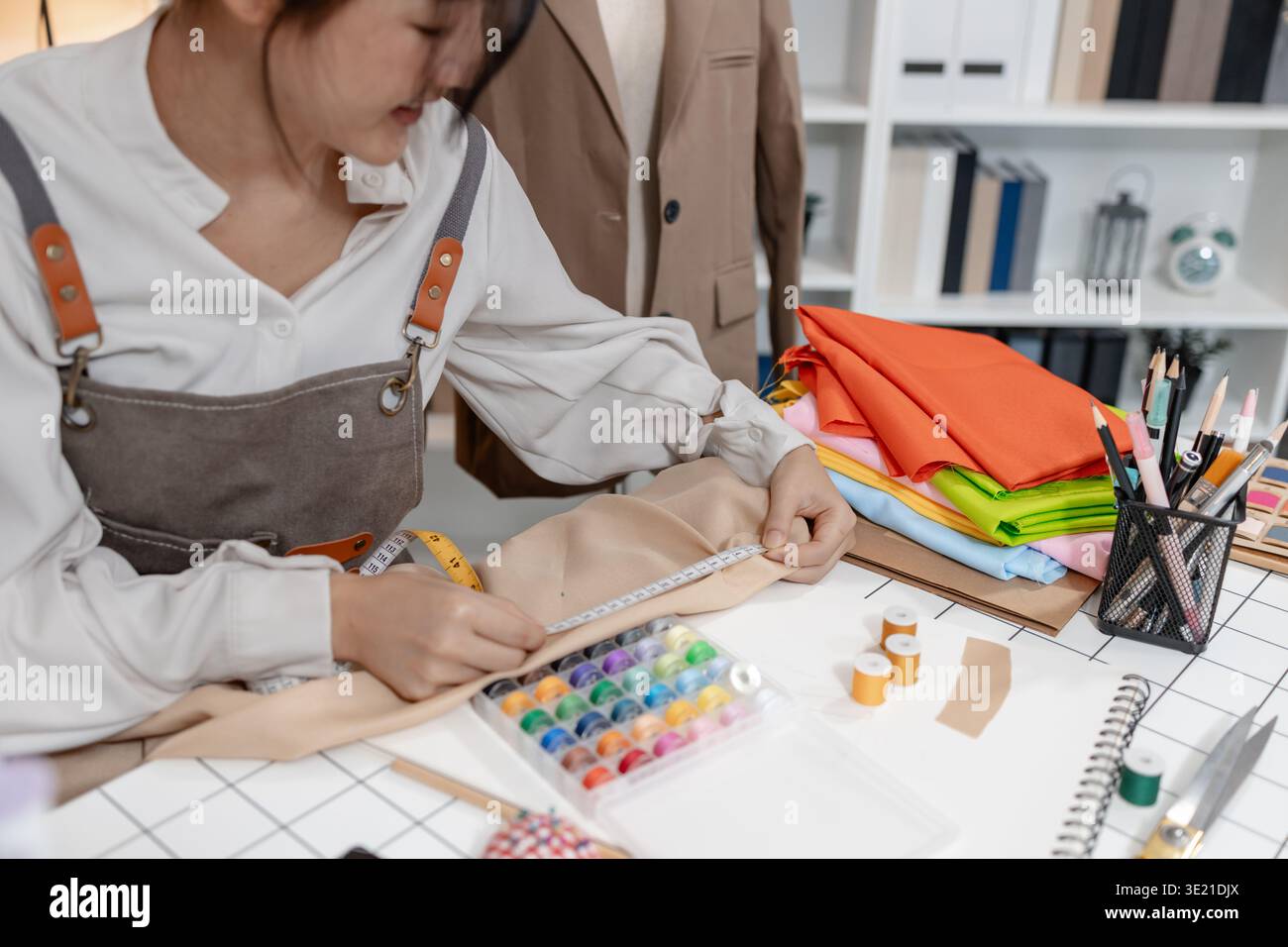 Créateur de mode mesurant le tissu et préparant des matériaux pour la production de vêtements tout en développant des patrons de vêtements et des idées de confection dans une profession Banque D'Images