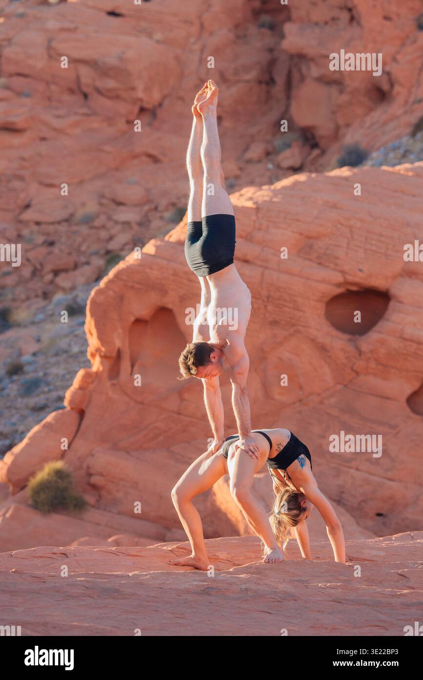 Acrobates effectuant une impressionnante pose sur les formations rocheuses rouges dans un paysage désertique. WA, ÉTATS-UNIS Banque D'Images