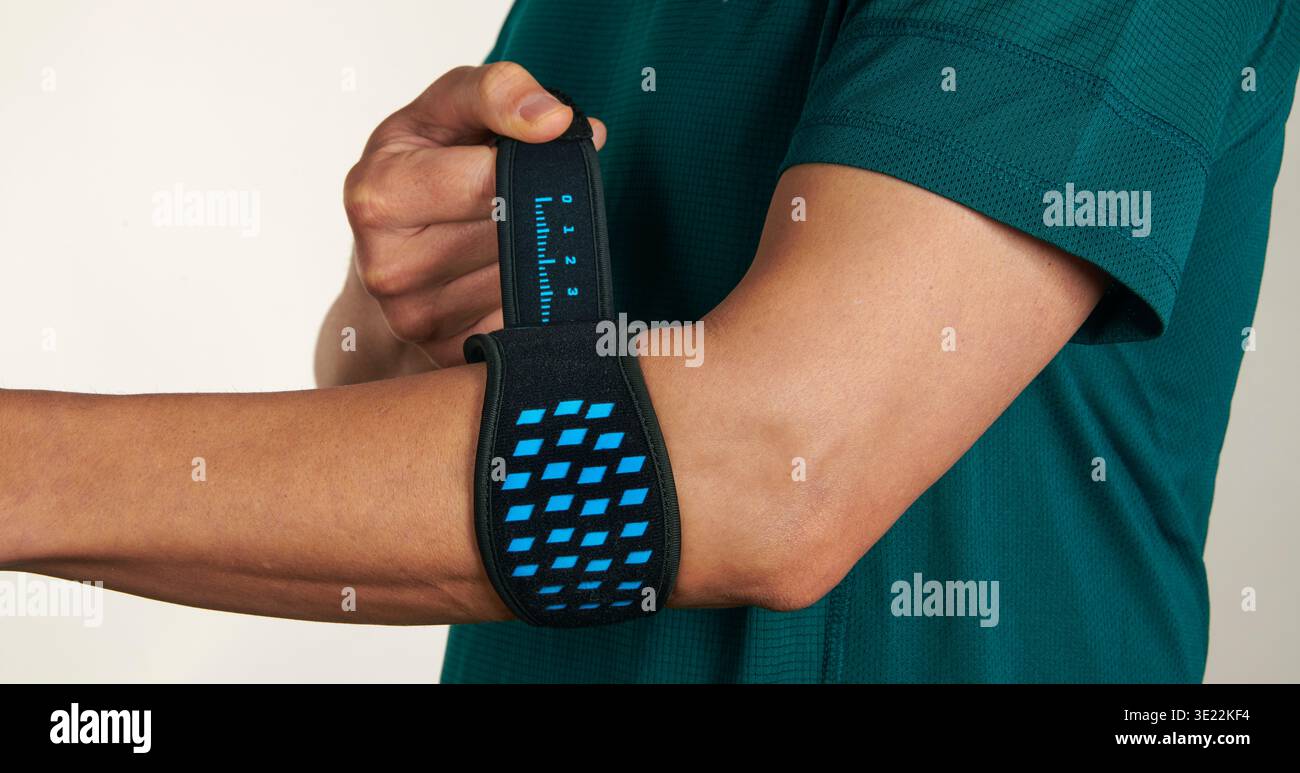gros plan d'un sportif ajustant une attelle d'épicondylite sur son coude, support orthopédique utilisé pour soulager la douleur au coude de tennis et réduire la tension sur le forea Banque D'Images