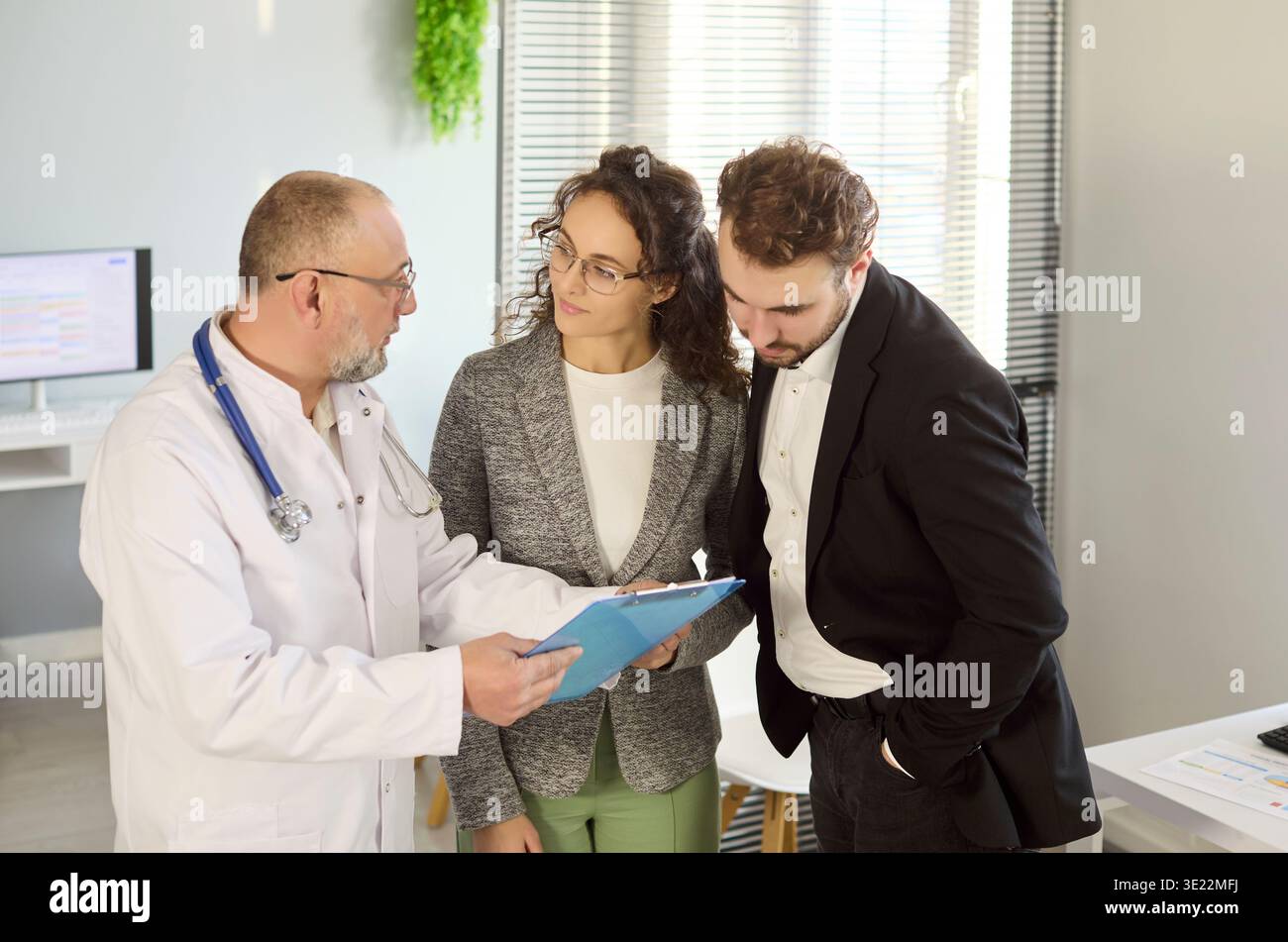 Médecin examinant les résultats médicaux avec couple en clinique, discutant des options du patient Banque D'Images