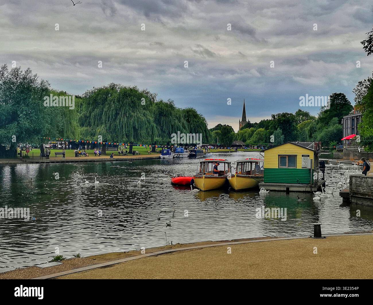 Vue panoramique de Stratford upon Avon avec la rivière Avon menant à l'église Holy Trinity, cygnes glissant sur l'eau et bateaux dérivent paisiblement. - Image de stock capturée avec un smartphone