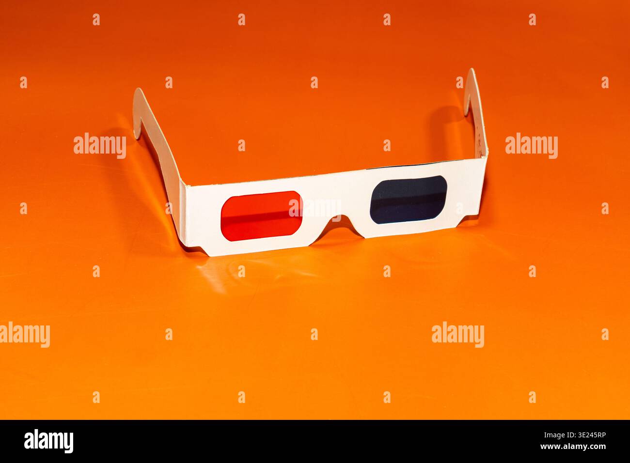 Une paire de lunettes 3D en carton rouge cyan sur fond orange. Banque D'Images