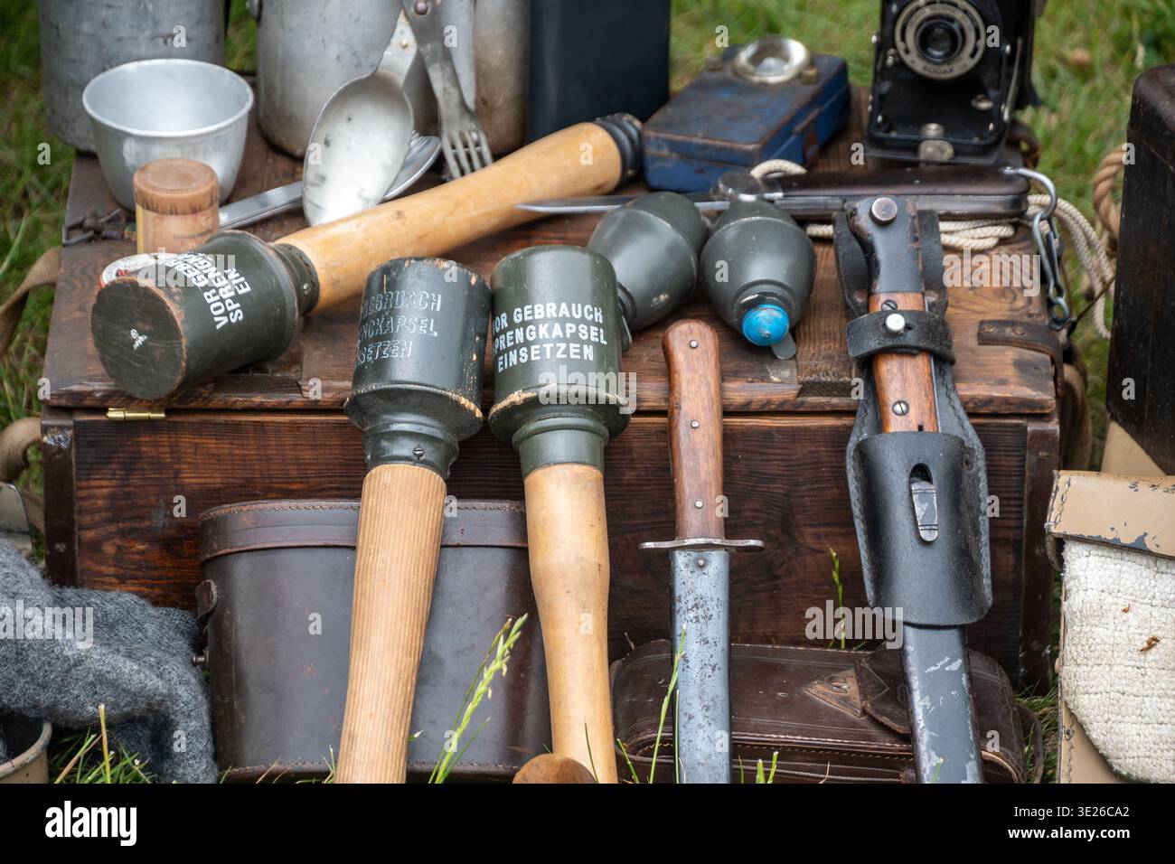 Headcorn Battle of Britain Airshow - gros plan de grenades allemandes vintage de la seconde Guerre mondiale, couteau à baïonnette, étuis en cuir et équipement de terrain disposés sur du bois Banque D'Images