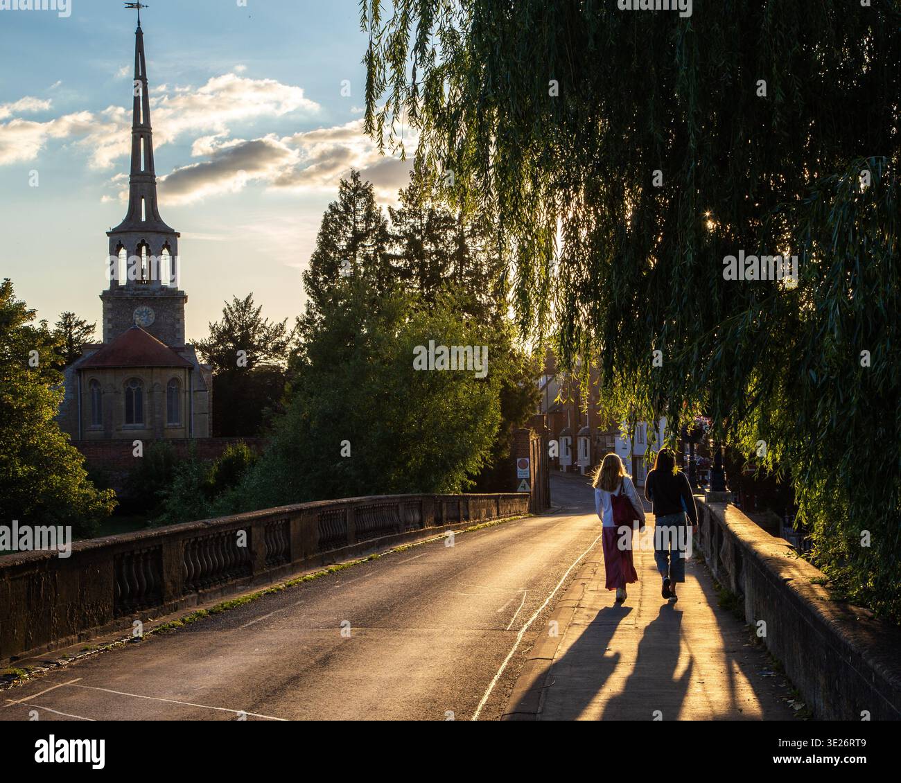 Deux personnes marchant sur le pont wallingford au coucher du soleil, avec l'église St peter en arrière-plan Banque D'Images
