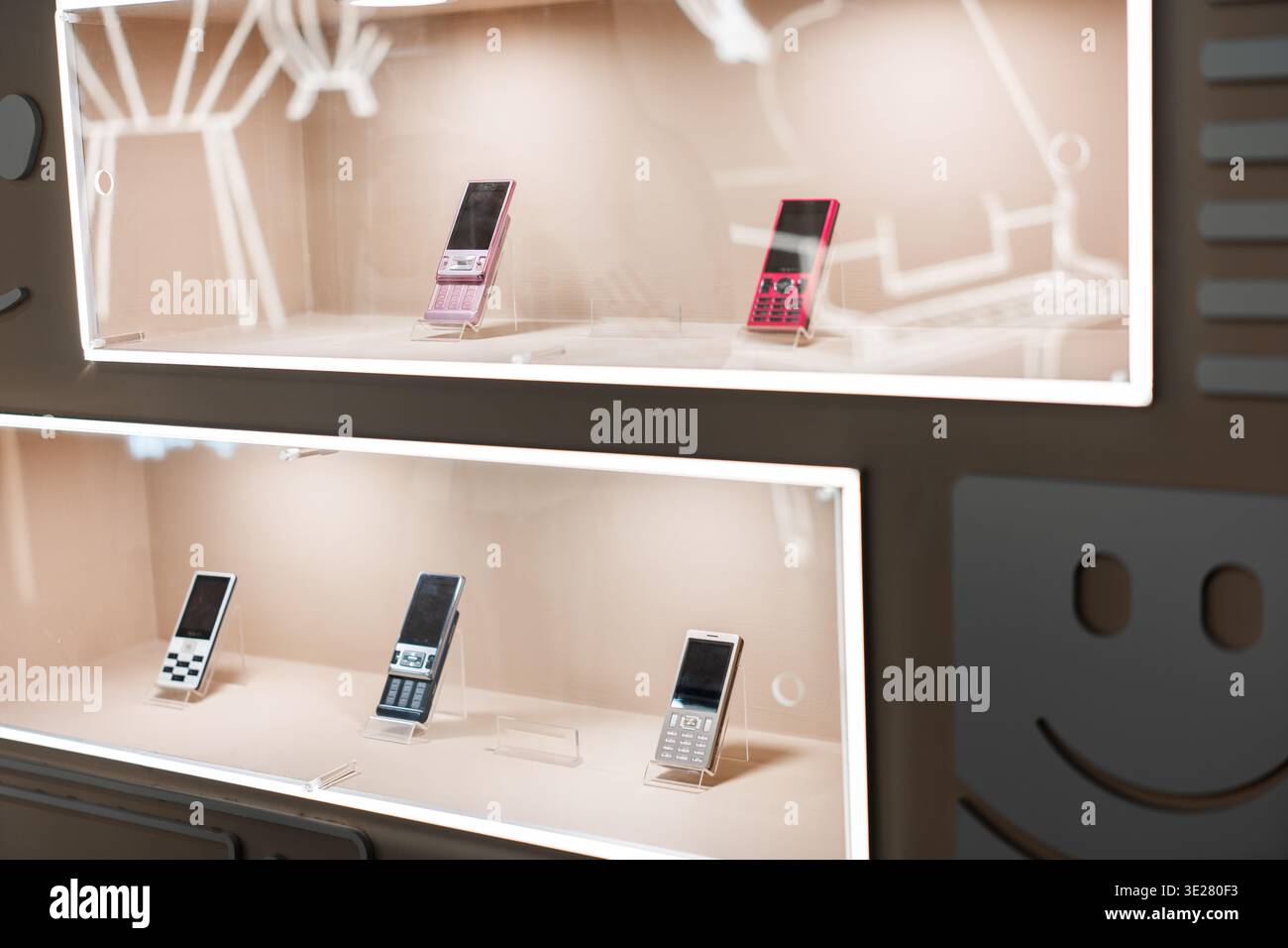 Téléphones portables vintage exposés dans des étuis en verre lumineux dans un magasin rétro tech à Tokyo, au Japon Banque D'Images
