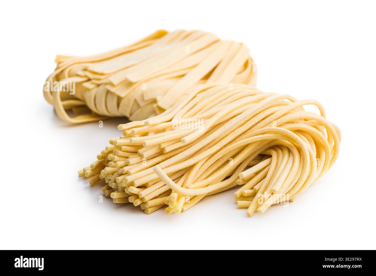 Des brins de fettuccine et de bigoli reposent sur une surface blanche, paraissant doux et frais. Ce type de pâtes est souvent utilisé dans divers plats. Banque D'Images