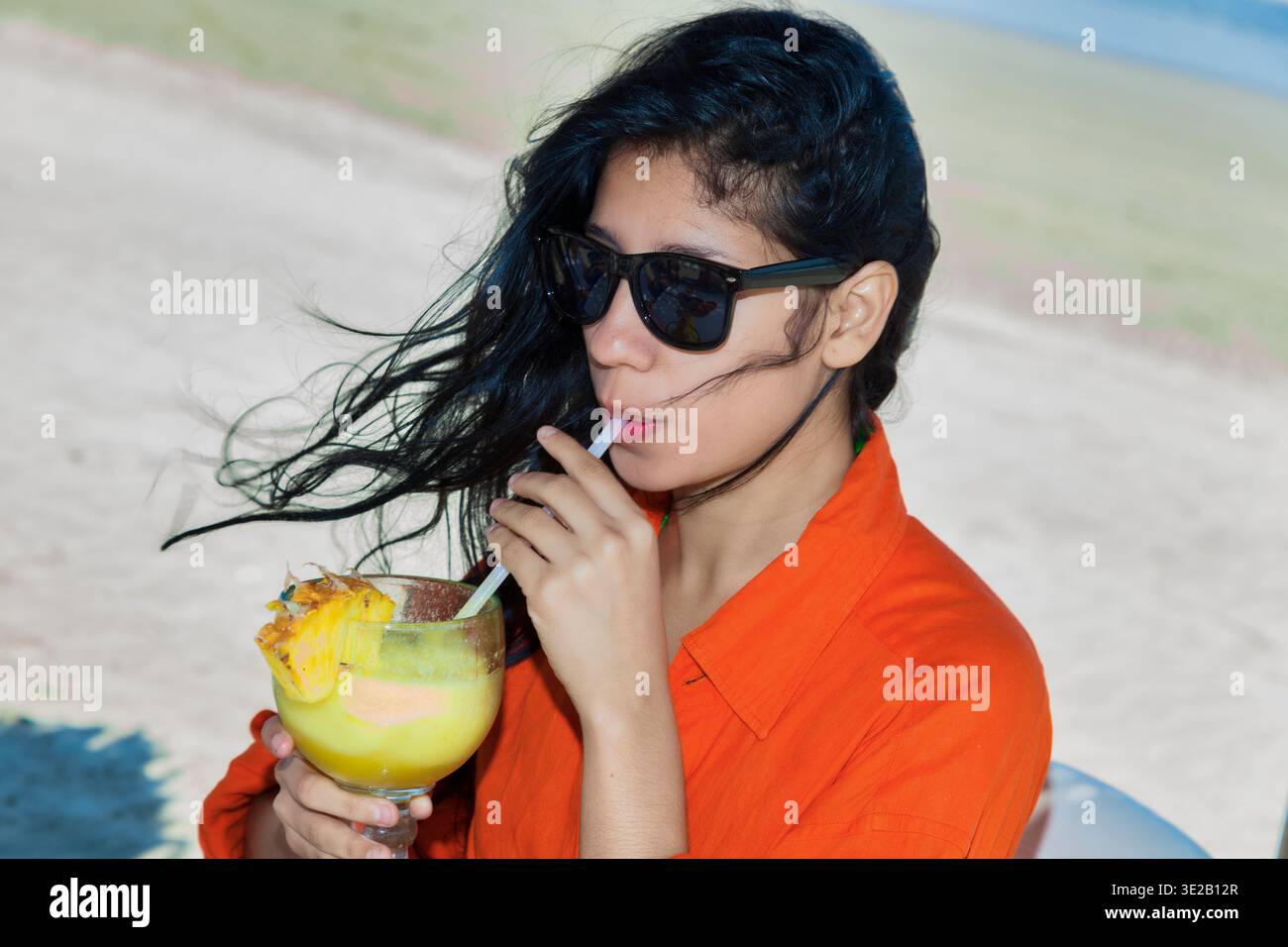 Femmes latines âgées de 20-30 ans buvant un cocktail jaune et de la bière sur une plage i au Mexique Banque D'Images
