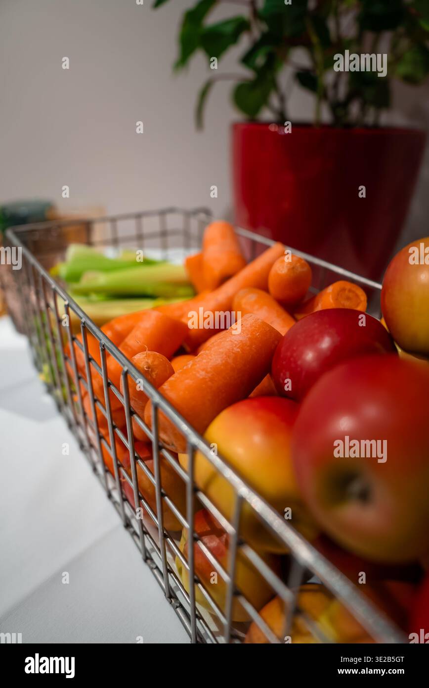 Panier en fil de métal avec carottes, pommes et céleri à Oberlech, Autriche Banque D'Images