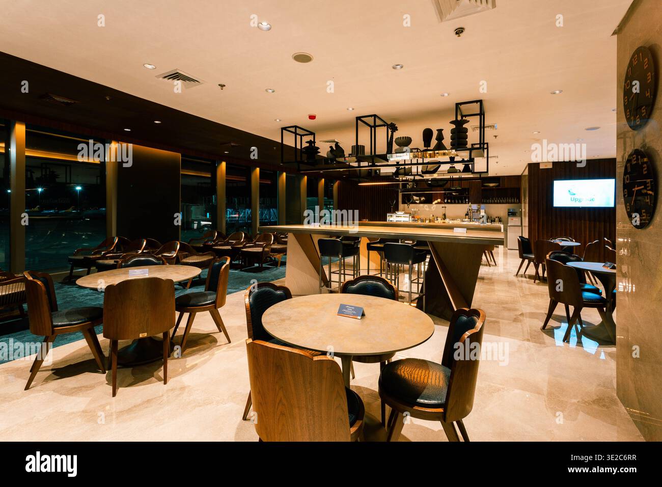 Lapu-Lapu, Philippines - 20 juillet 2018 : vue sur un salon élégant avec des tables rondes en bois, des chaises sombres et un bar élégant sous un éclairage chaleureux, invi Banque D'Images