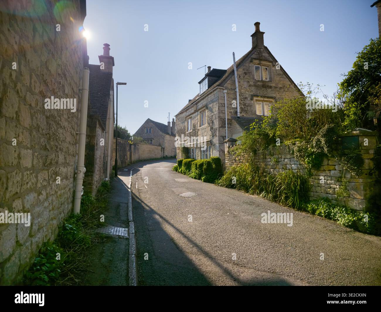 Sunlit Narrow Cotswold Lane avec Honey Stone Houses et Lens Flare, Painswick Area, Gloucestershire, Angleterre - Image de stock capturée avec un smartphone
