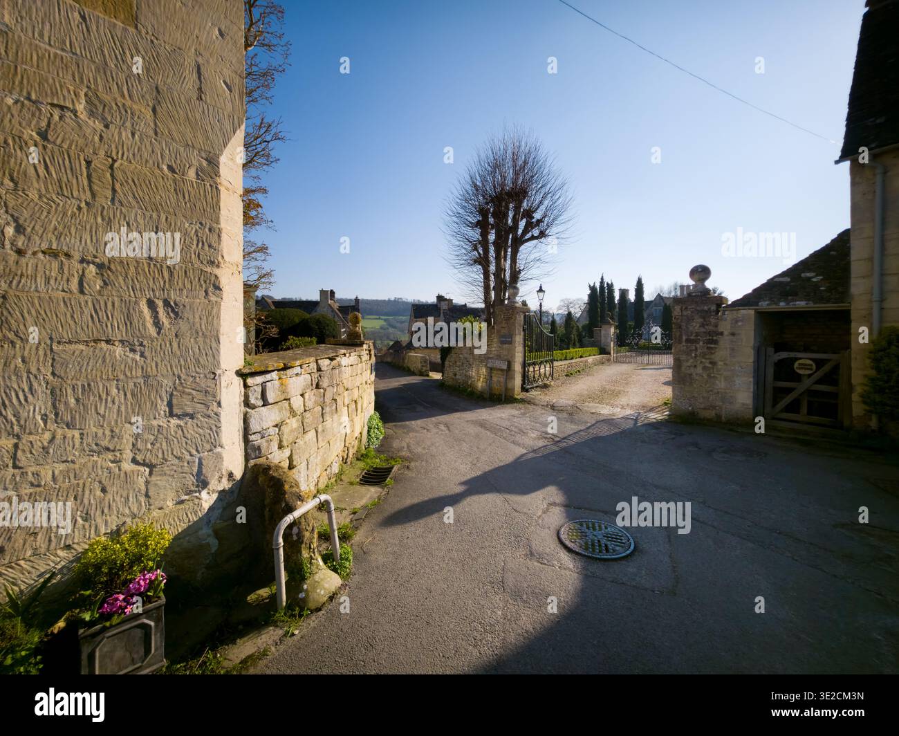 Sunlit Narrow Cotswold Lane avec Honey Stone Houses et Lens Flare, Painswick Area, Gloucestershire, Angleterre - Image de stock capturée avec un smartphone