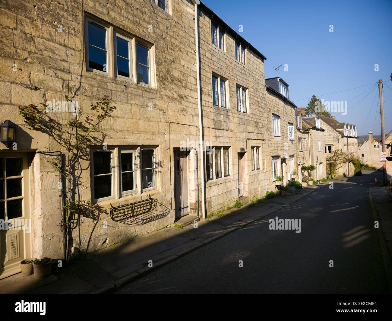 Sunlit Narrow Cotswold Lane avec Honey Stone Houses et Lens Flare, Painswick Area, Gloucestershire, Angleterre - Image de stock capturée avec un smartphone